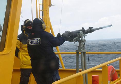 Customs officers fire a machine-gun on board Oceanic Viking